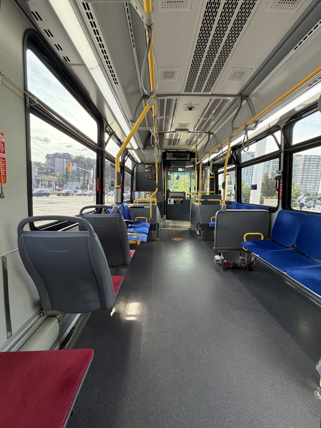 Interior of TTC bus 3466 looking toward the front door, with blue seats and yellow handrails.