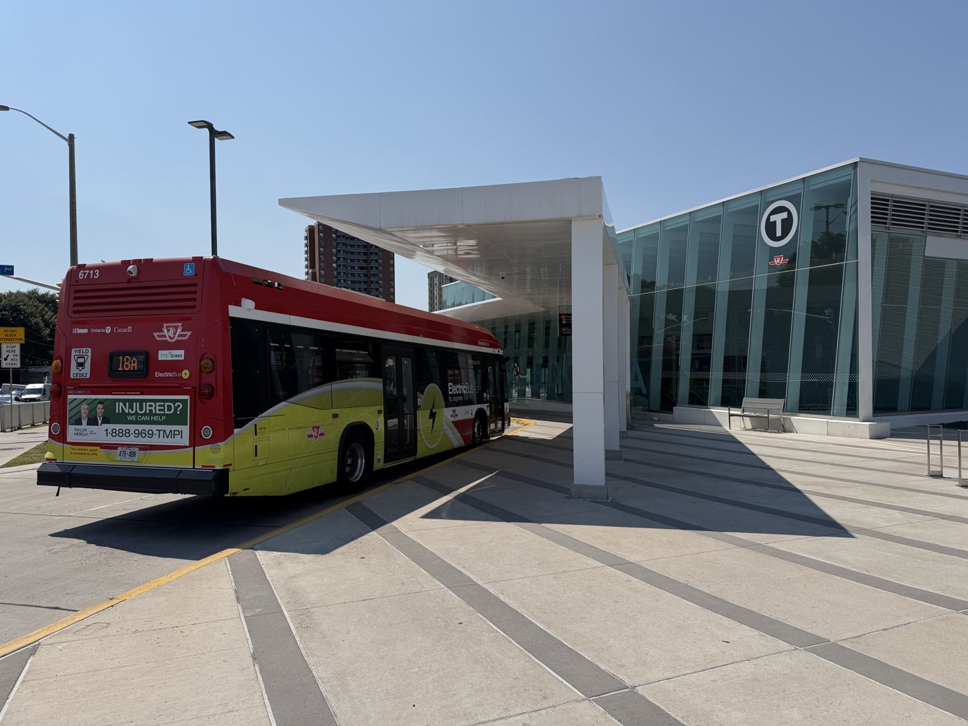 TTC electric bus 6713 displaying route 18A beside a glass station entrance.